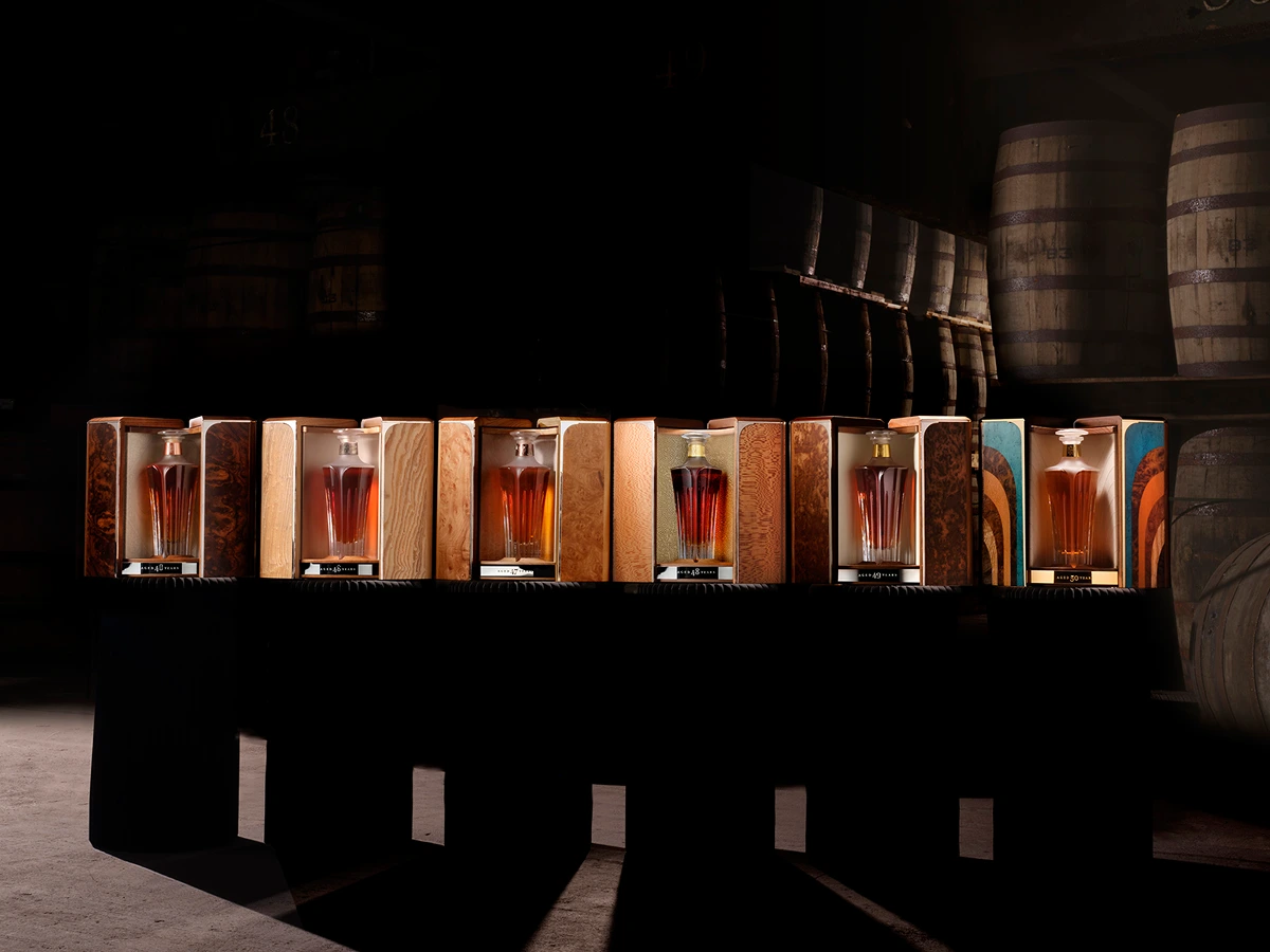 Midleton Very Rare Silent Distillery Collection featuring six exquisite whiskey decanters displayed in handcrafted wooden cases inside a traditional Irish barrel warehouse.