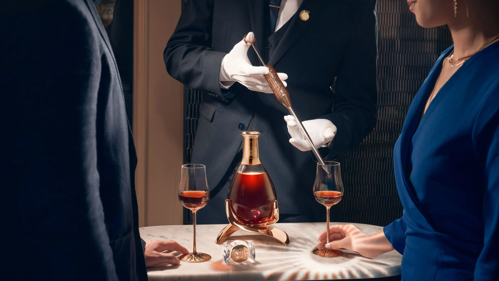 Close-up of a white-gloved host pouring Perrier-Jouët champagne into vintage crystal glasses